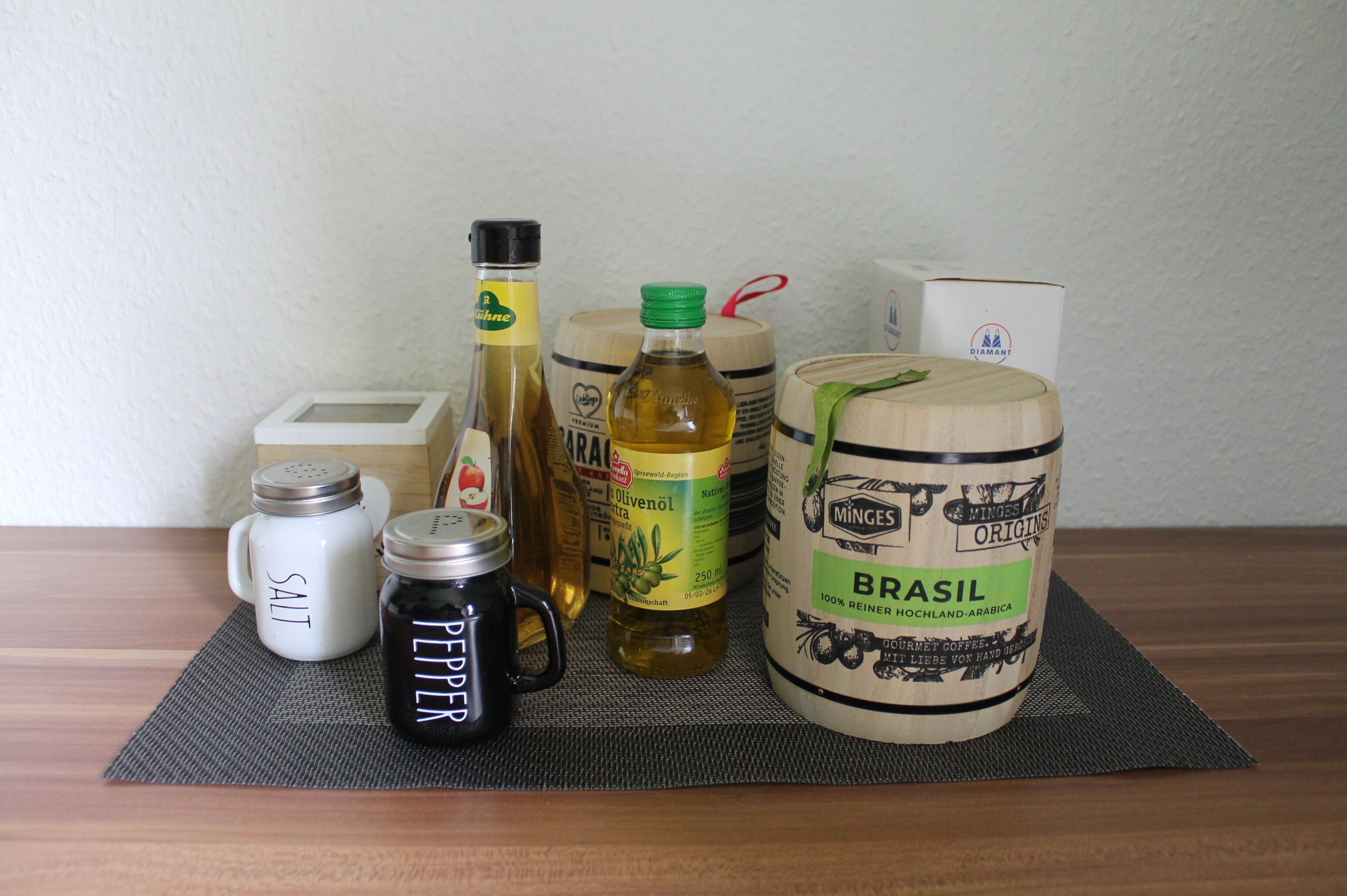 A kitchen counter with various food items including a salt shaker, pepper shaker, olive oil, and a large container labeled 'BRASIL'.