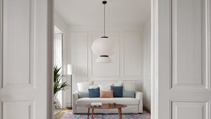 Ein helles Zimmer mit einer Couch, einem Couchtisch und einer Pendelleuchte.