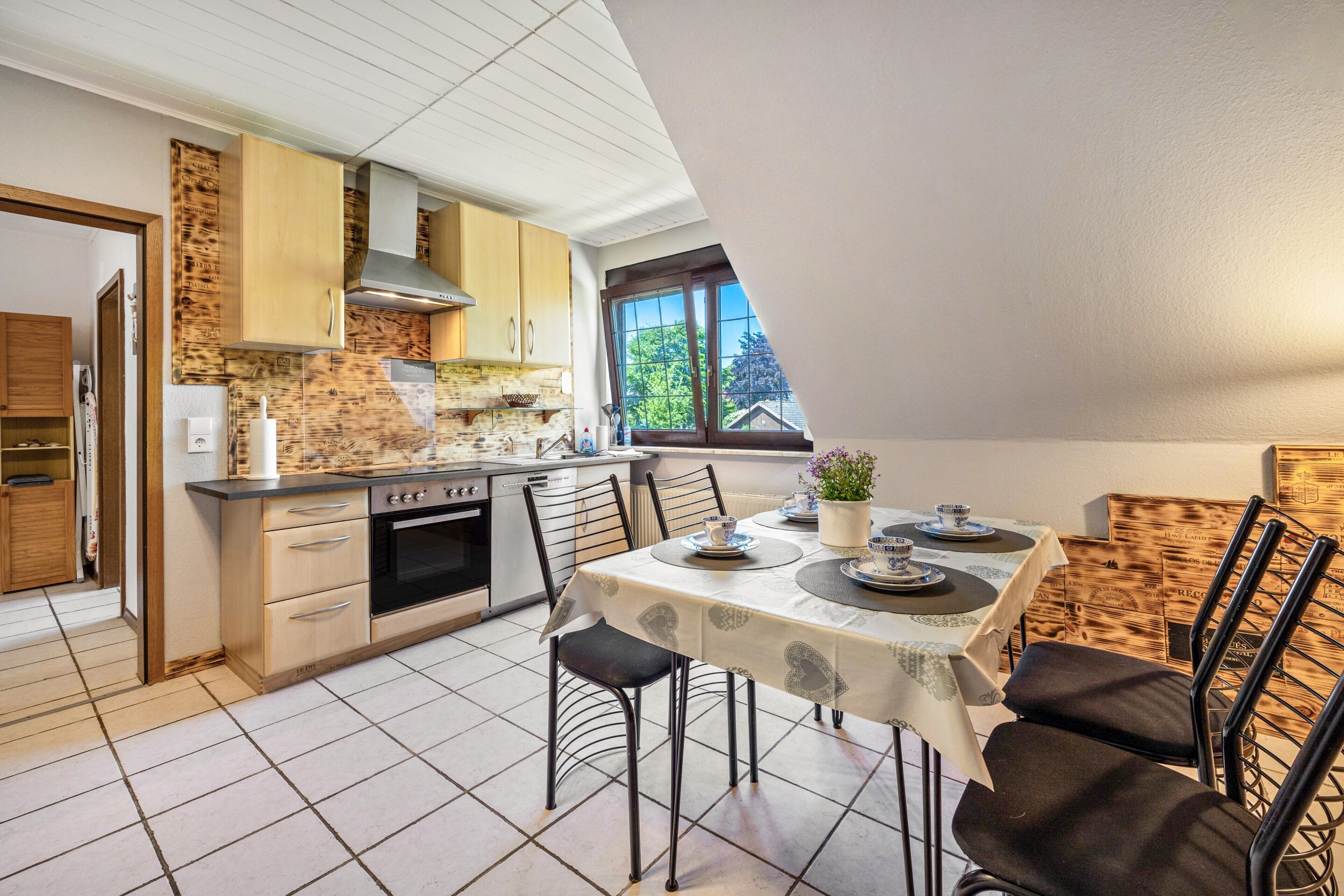 A kitchen with a dining area, featuring a table set for two, a stove, and cabinets.