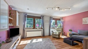 A modern living room with a flat-screen TV, a sofa, a chair, and a coffee table. - Apartment 'Storchenallee' (Burg (Dithmarschen))
