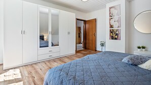A bedroom with a bed, wardrobe, and a door leading to another room. - Apartment 'Storchenallee' (Burg (Dithmarschen))