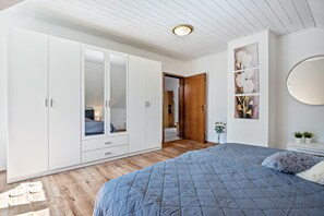 Ein Schlafzimmer mit Bett, Schrank und einer Tür zu einem anderen Raum.