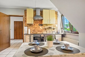 Eine moderne Küche mit Holzschränken, einem Gasherd und einem Essbereich mit Tisch für vier Personen.