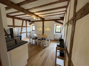 Una cocina con techo de madera, un comedor con mesa y sillas, y un ventanal con vistas.