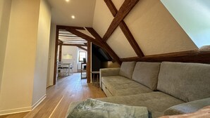 Une pièce de style « loft », avec des poutres en bois apparentes, un canapé et un coin repas à l’arrière-plan.