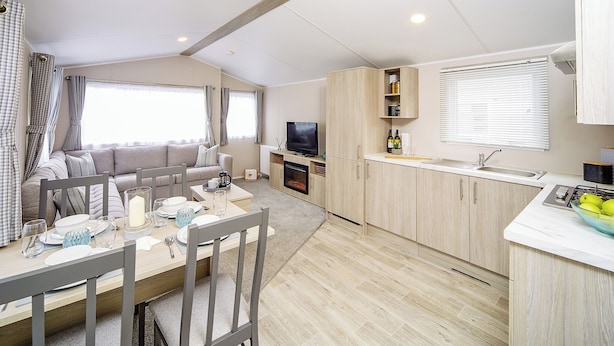 A modern RV interior with a dining area, kitchen, and living space.