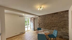 Un espace repas avec un mur en pierre, un plancher en bois et des chaises bleues.