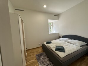 Un dormitorio con una cama, una ventana, una puerta y una alfombra pequeña.
