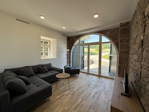 Una sala de estar moderna con un sofá modular, una mesita redonda y un mueble para la televisión.