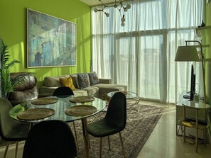 A modern living room with a glass coffee table, leather sofa, and a large abstract painting on the wall. - 1BR Penthouse in Millenium Binghatti  (Dubai)