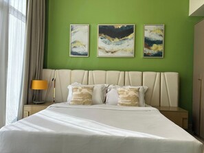 A hotel room with a large bed, a nightstand with a lamp, and three abstract paintings on the wall. - 1BR Penthouse in Millenium Binghatti  (Dubai)