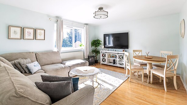 A living room with a sofa, a coffee table, a TV, and a dining area with chairs and a table. - Quiet and Cosy 2-bed in Wimbledon (London)