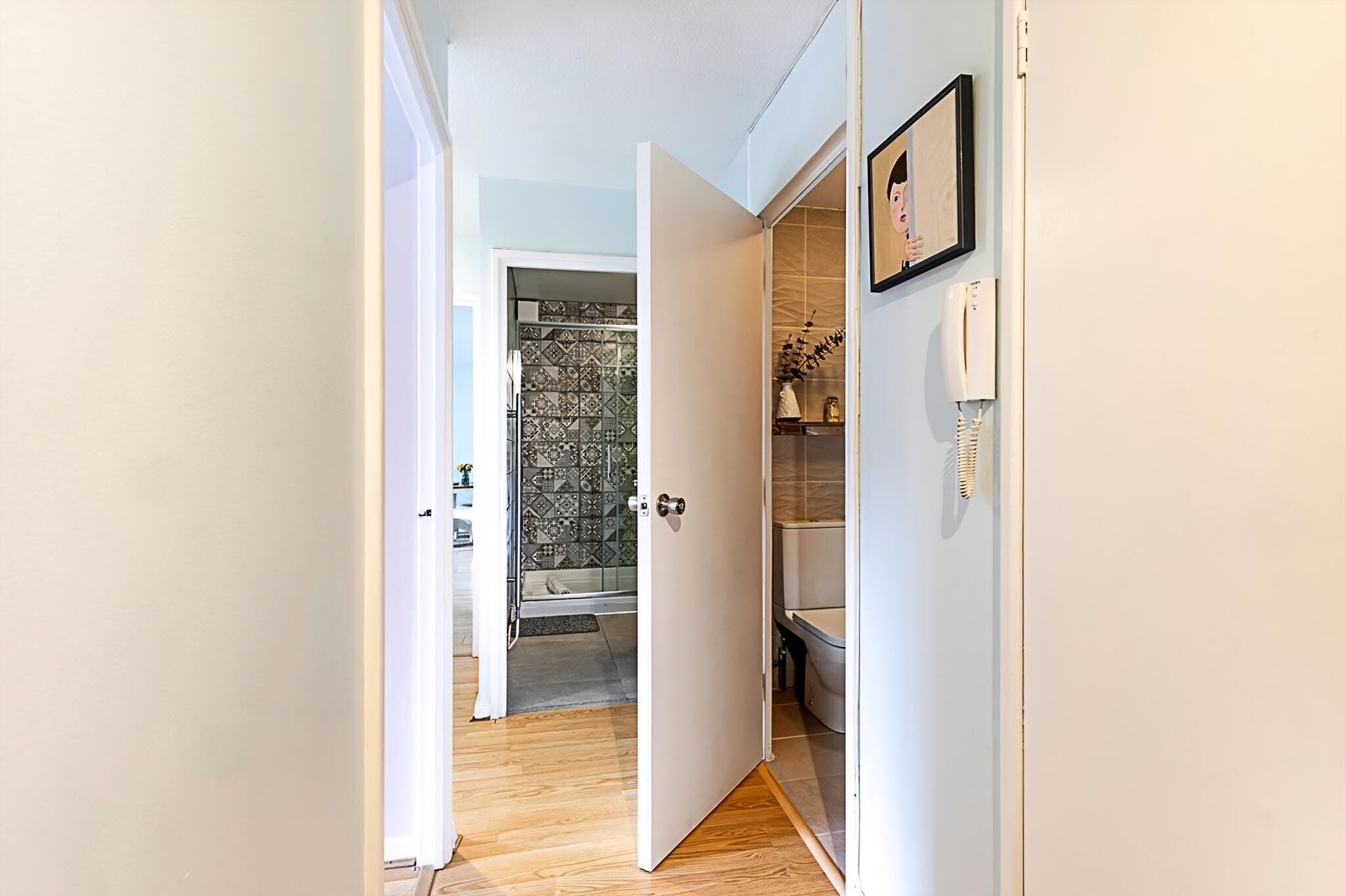 Un couloir avec une porte donnant sur une salle de bain dont le sol est recouvert de carreaux décoratifs.