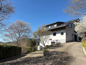 A two-story house with a sloped roof, a covered porch, and a paved driveway.