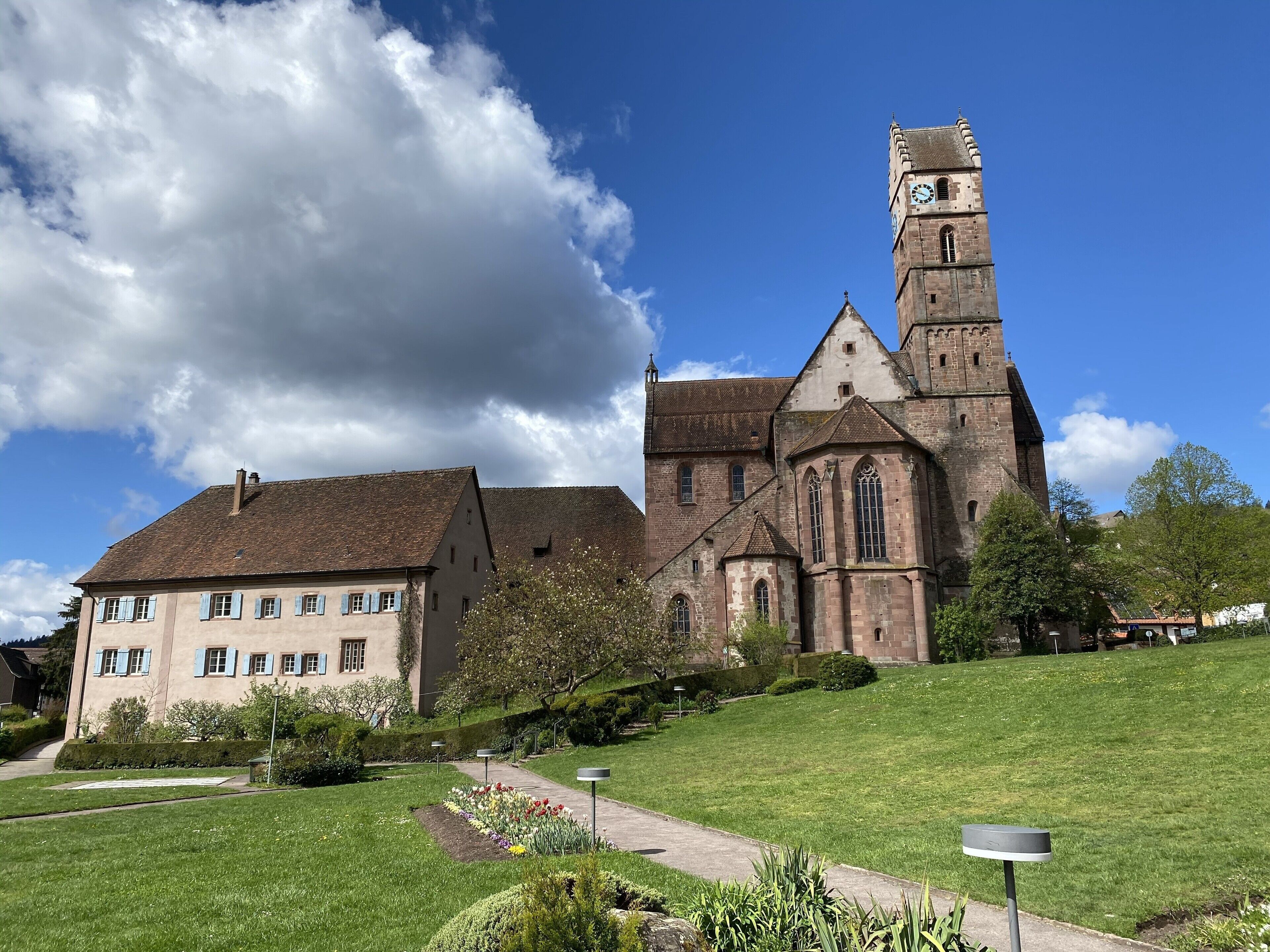 A historic church with a prominent tower and a smaller building with blue shutters.
