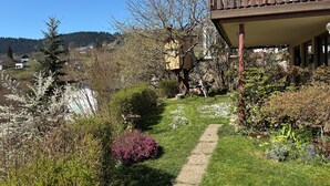 Ein Gartenweg führt zu einer Holzterrasse mit Blick auf eine Berglandschaft.