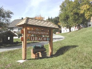 Une pancarte en bois sur laquelle est inscrit « Willkommen in URACH », indiquant qu’il s’agit d’une signalisation d’accueil pour un lieu appelé URACH.