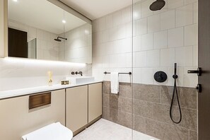 Ein modernes Badezimmer mit großem Spiegel, Waschbecken, Toilette und Duschbereich.