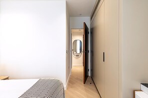 Ein modernes Schlafzimmer mit Bett, Kleiderschrank und einem Flur, der zum Badezimmer führt.