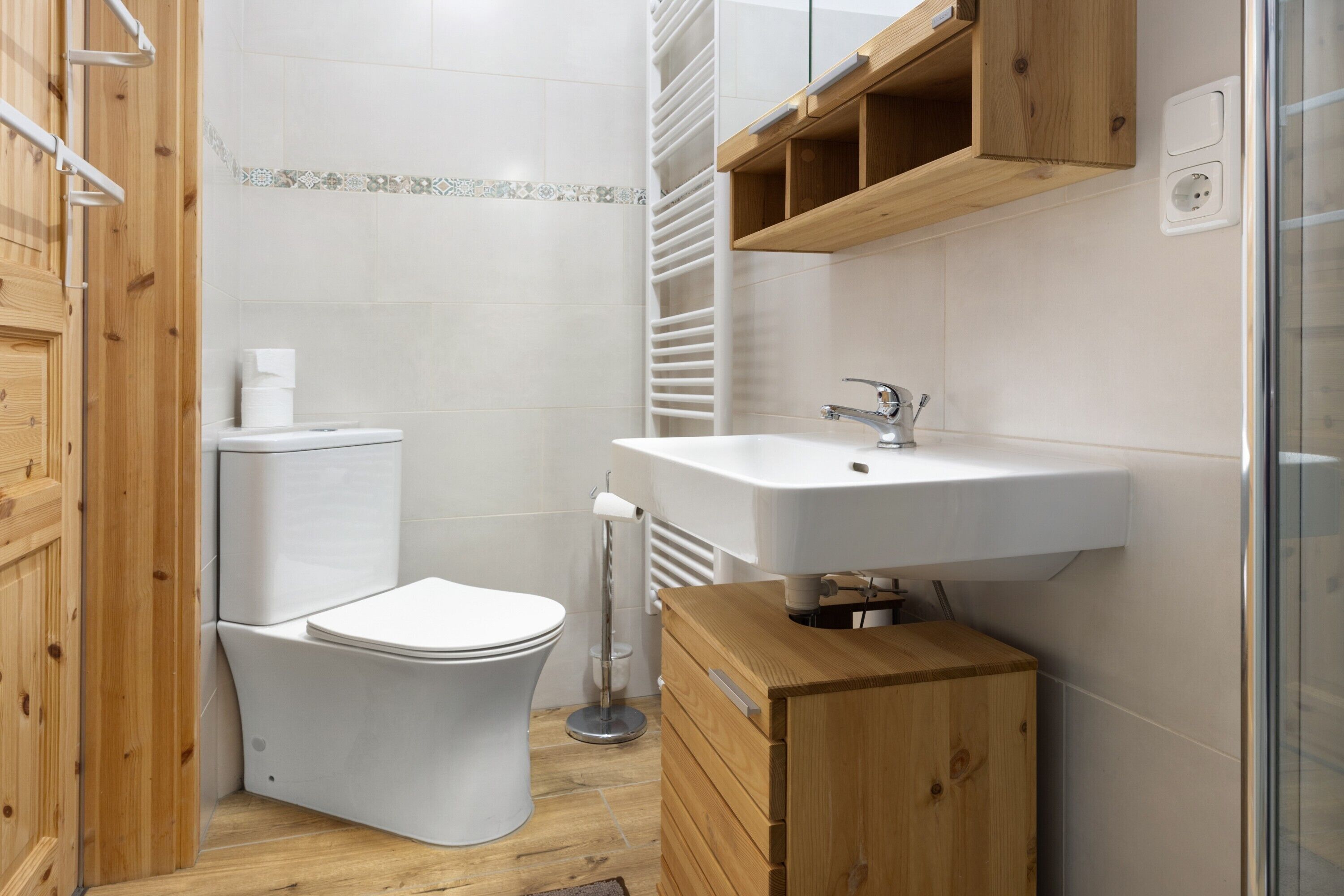 A bathroom with a toilet, sink, wooden cabinet, and a towel rack.