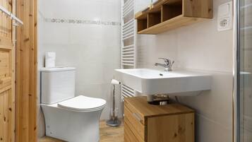 A bathroom with a toilet, sink, wooden cabinet, and a towel rack.
