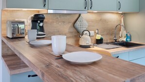 Una cocina con encimera de madera, un tostador, una cafetera, un hervidor y un lavabo.