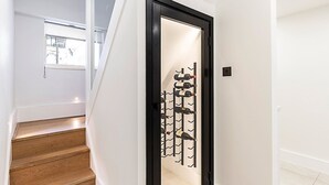 Eine Treppe führt zu einem Raum mit einem Weinkühlschrank, der mehrere Flaschen beherbergt.