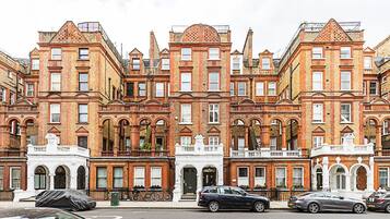 A row of red brick townhouses with white facades, arched windows, and a central white building with a dome.