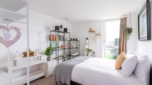 Ein modernes Schlafzimmer mit einem Bett, weißen Regalen, einer herzförmigen Dekoration und einem Fenster mit Vorhängen.