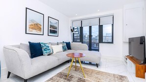 Een moderne woonkamer met een bank, een ronde salontafel en een flatscreen televisie.