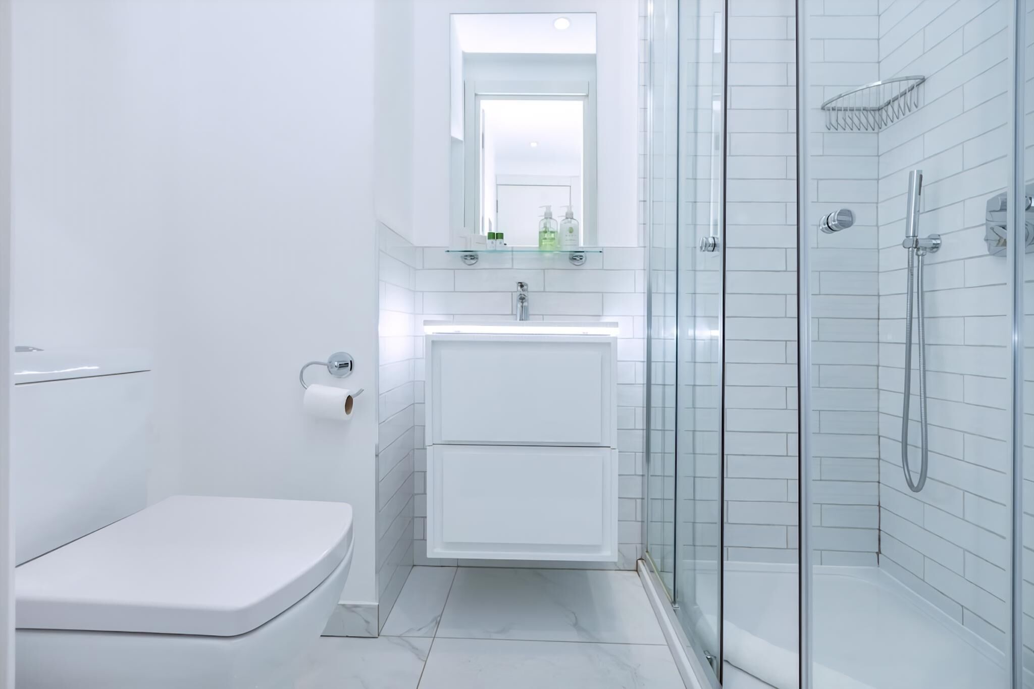 A modern bathroom with a toilet, sink, and glass-enclosed shower.