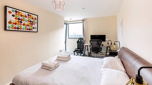 A hotel room with a large bed, a desk with a computer, a chair, and a window with a view.