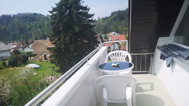 A balcony with a small table and two chairs, overlooking a residential area with houses and trees. - Apartment 'Eckert' with Shared Garden, Balcony and Wi-Fi (Wehr)