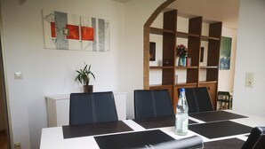 A conference room with a white table, black chairs, a potted plant, and a bookshelf. - Apartment 'Eckert' with Shared Garden, Balcony and Wi-Fi (Wehr)