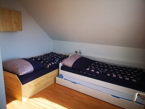 Una habitación pequeña con dos literas de madera, un armario de madera y una pared blanca.
