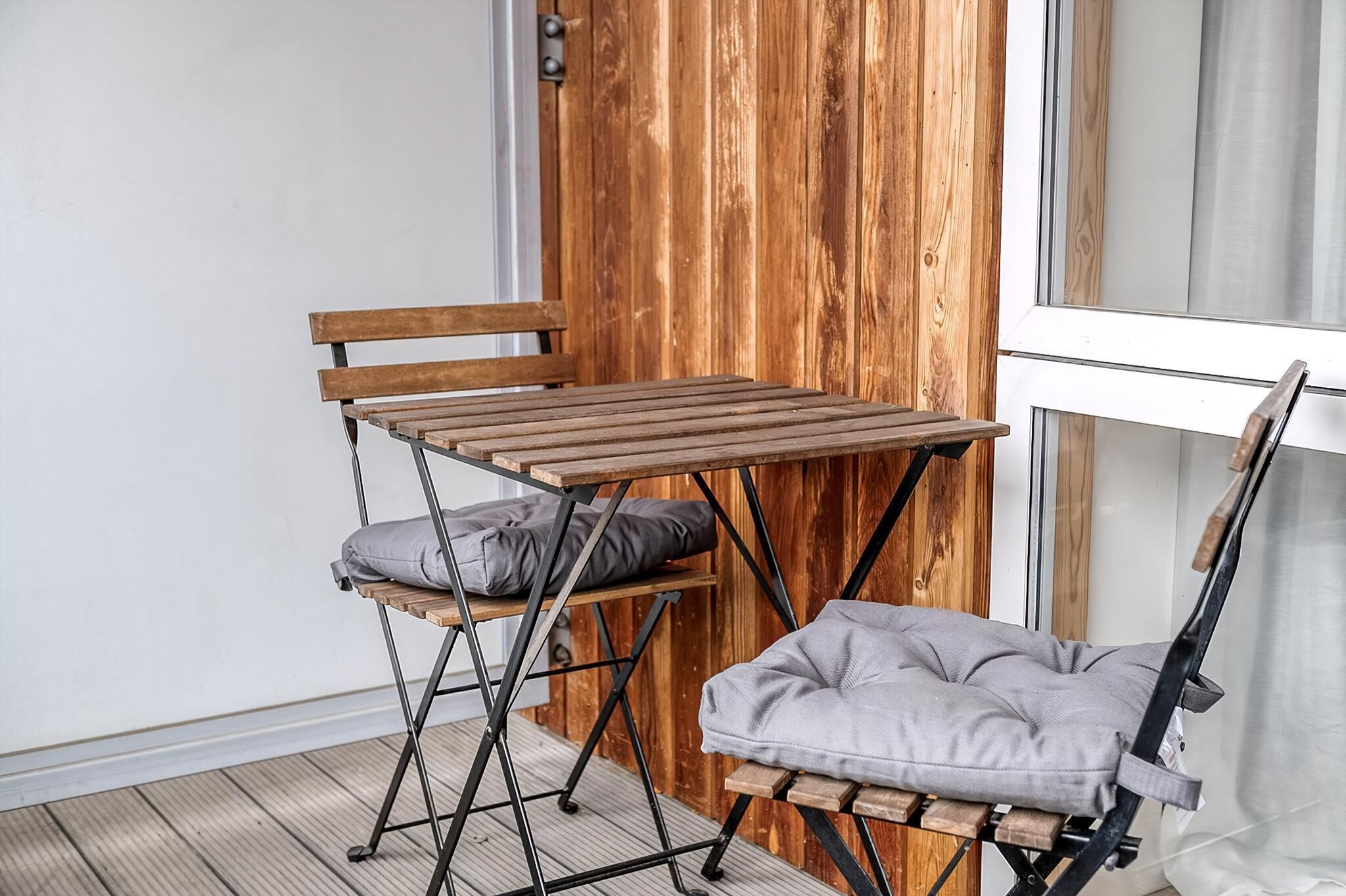 A compact, foldable table with a bench, positioned against a wooden wall with a window.