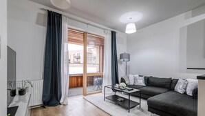 Una sala de estar moderna con un sofá gris oscuro, una mesa de centro de vidrio y un radiador blanco.