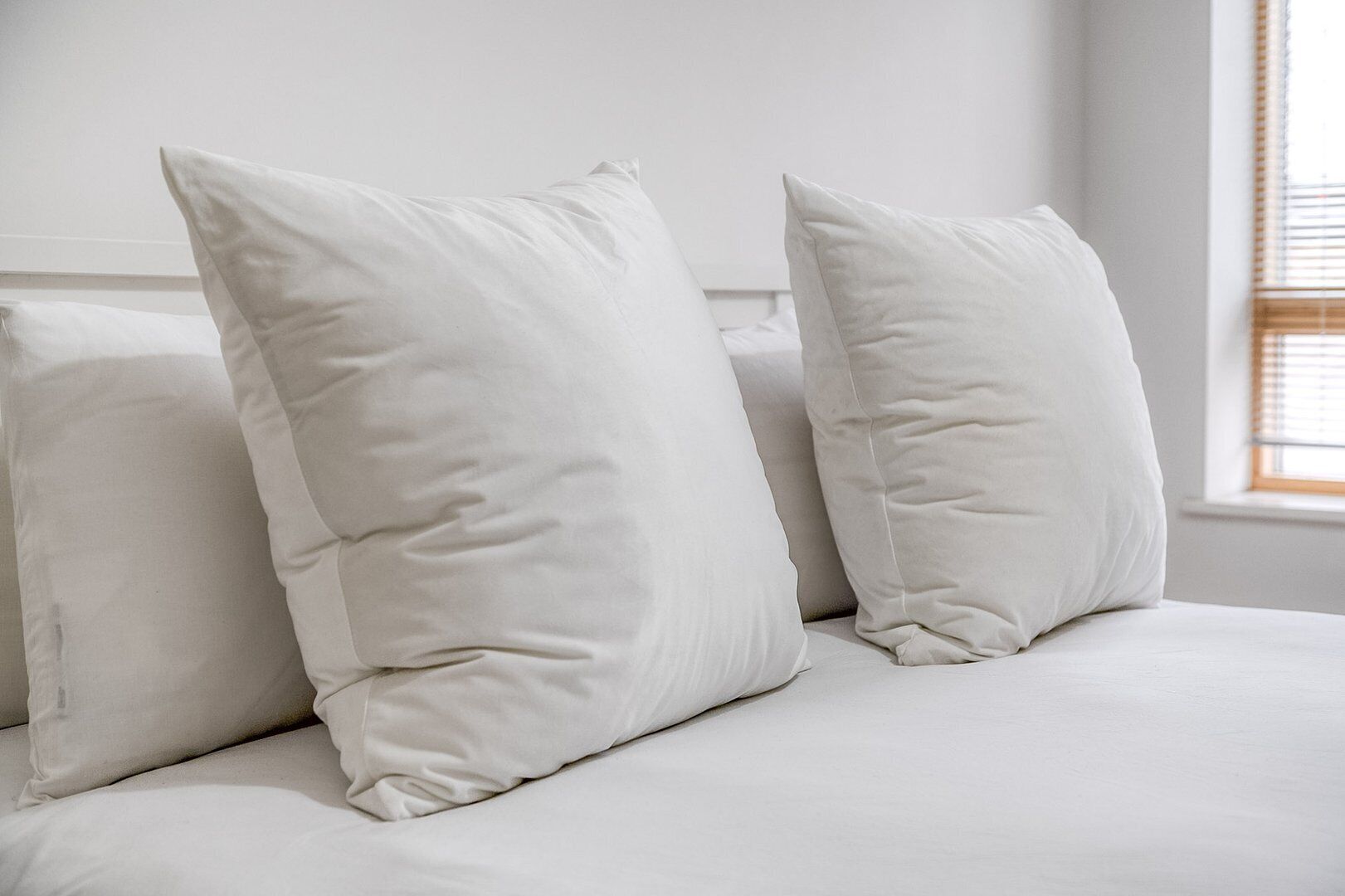 A bed with white bedding and pillows.