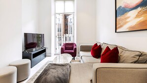 A modern living room with a sofa, armchairs, a coffee table, and a TV.