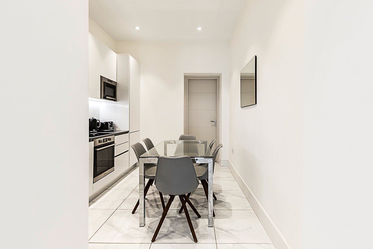 A compact kitchen with modern appliances, a dining table with chairs, and a door leading to another room.