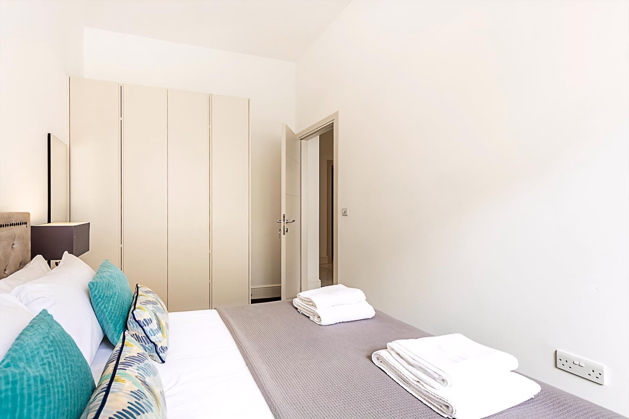 Une chambre d’hôtel équipée d’un lit, d’une armoire, d’une table de chevet et d’une prise électrique.