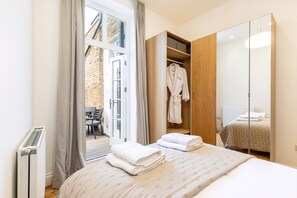 A bedroom with a large bed, a wardrobe, and a view of an outdoor seating area.