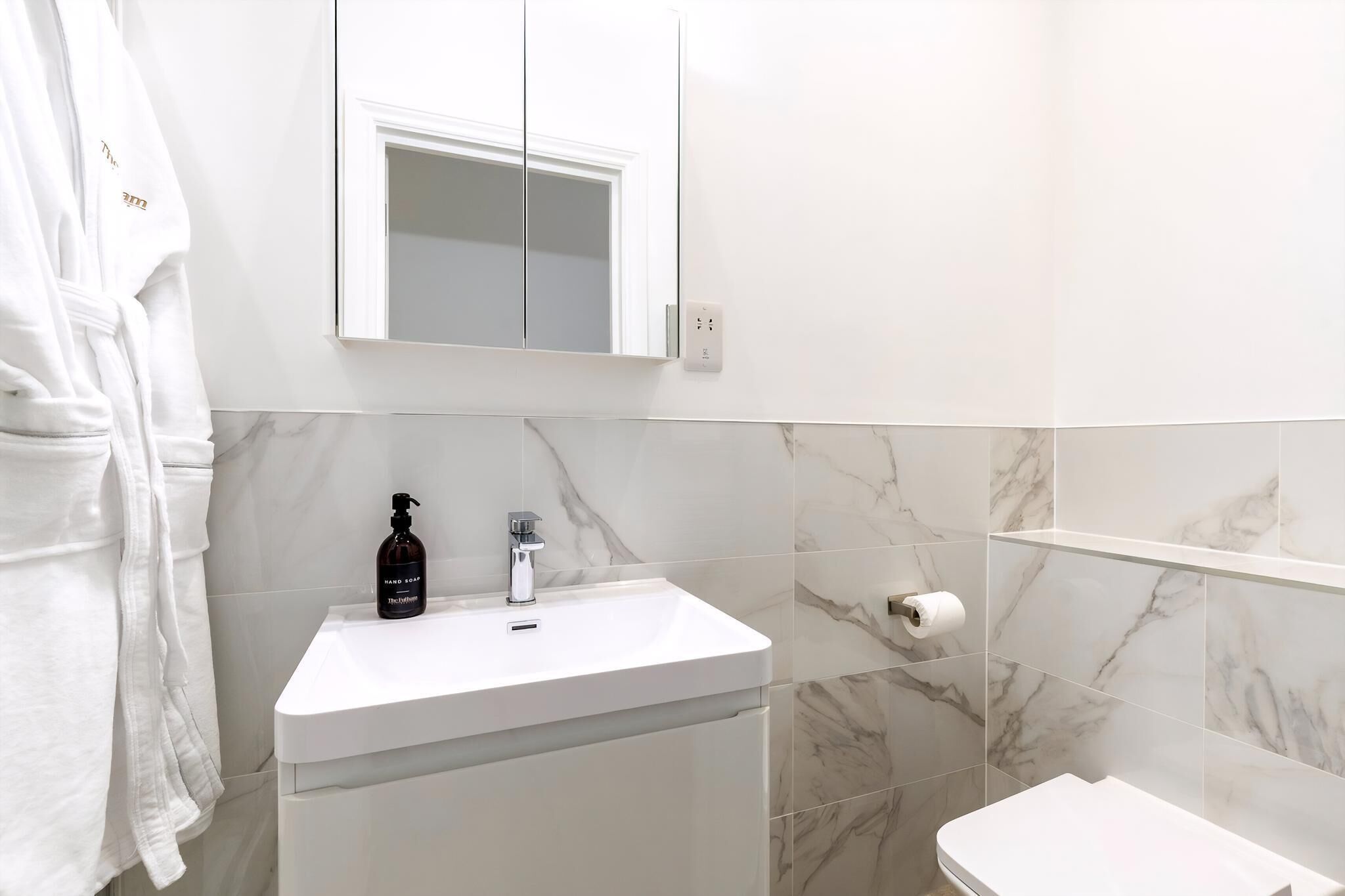 A bathroom with a white sink, a mirror above it, and a toilet.