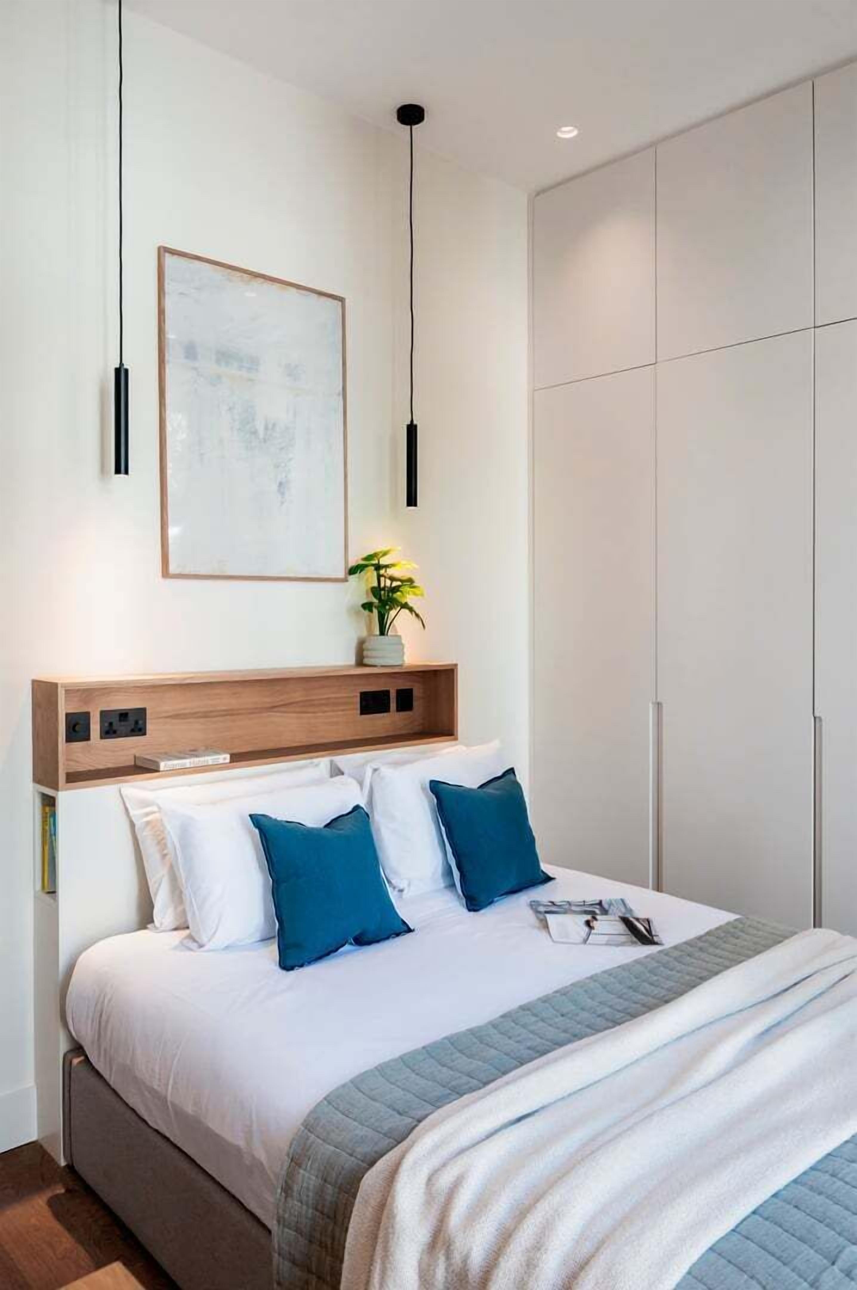 A modern bedroom with a bed, bedside table, and a large wardrobe.