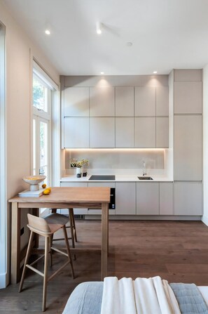 Una cocina moderna con armarios empotrados, una mesa de comedor de madera y un taburete de bar.