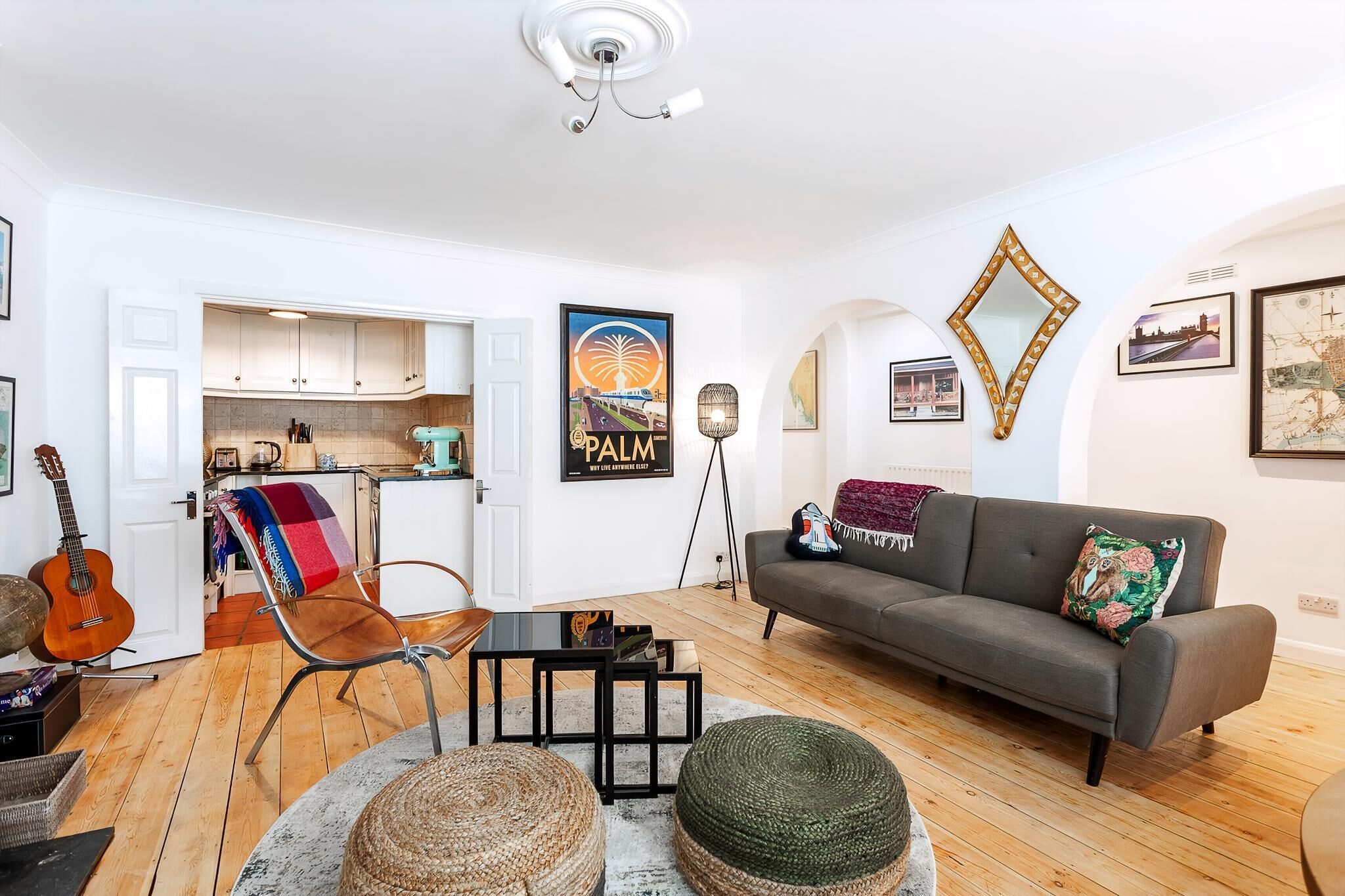 A modern living room with a grey sofa, a coffee table, and a dining area with a kitchen in the background.