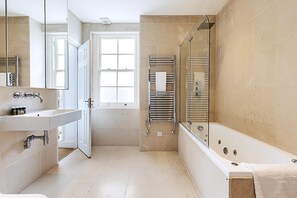 Une salle de bain moderne dotée d’une grande baignoire, d’une douche à l’italienne et d’un meuble-lavabo avec un miroir.