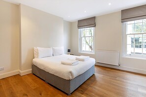 Une chambre à coucher avec un grand lit, un radiateur et deux fenêtres.