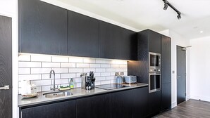 Una cocina moderna con armarios oscuros, un lavamanos de acero inoxidable, un microondas y un tostador.