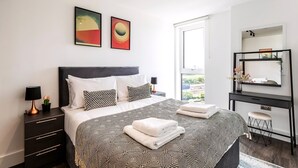 Un dormitorio moderno con una cama grande, un tocador, una cómoda y dos cuadros abstractos en la pared.